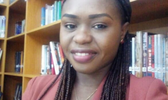 Author Akudo Chukwuma in front of a bookshelf