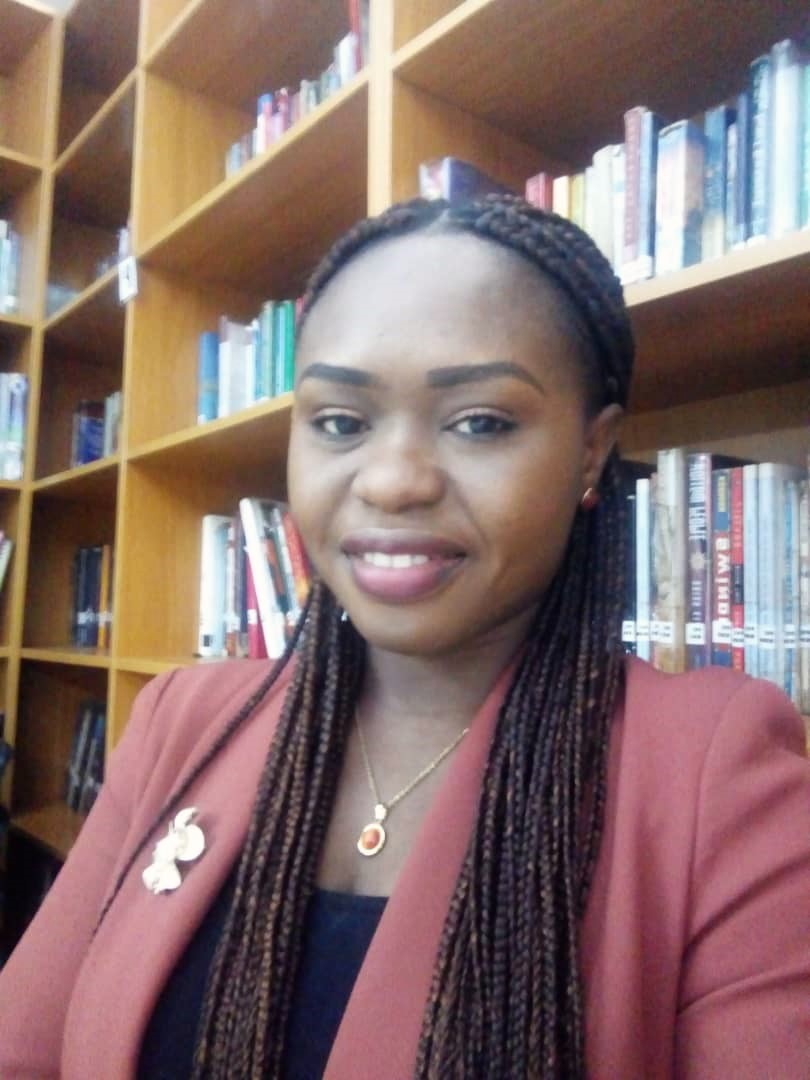 Author Akudo Chukwuma in front of a bookshelf